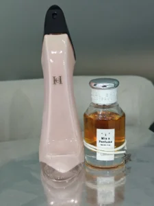 Side-by-side comparison of the Carolina Herrera Good Girl stiletto bottle and a minimalist factory-direct perfume dupe bottle.