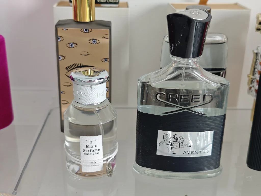 Cost and quality comparison between a $400 luxury Creed Aventus bottle and an affordable direct-to-consumer dupe perfume.