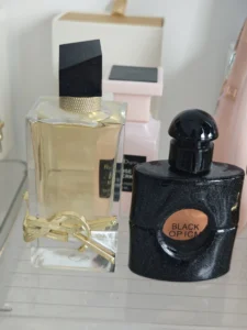 Side-by-side comparison of an expensive YSL Black Opium designer fragrance bottle and a long-lasting affordable perfume dupe