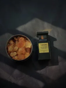 Luxury warm spicy amber fragrance comparison showing Virginia tobacco leaf, cacao, and Madagascar bourbon vanilla notes in high-concentration perfume dupes.